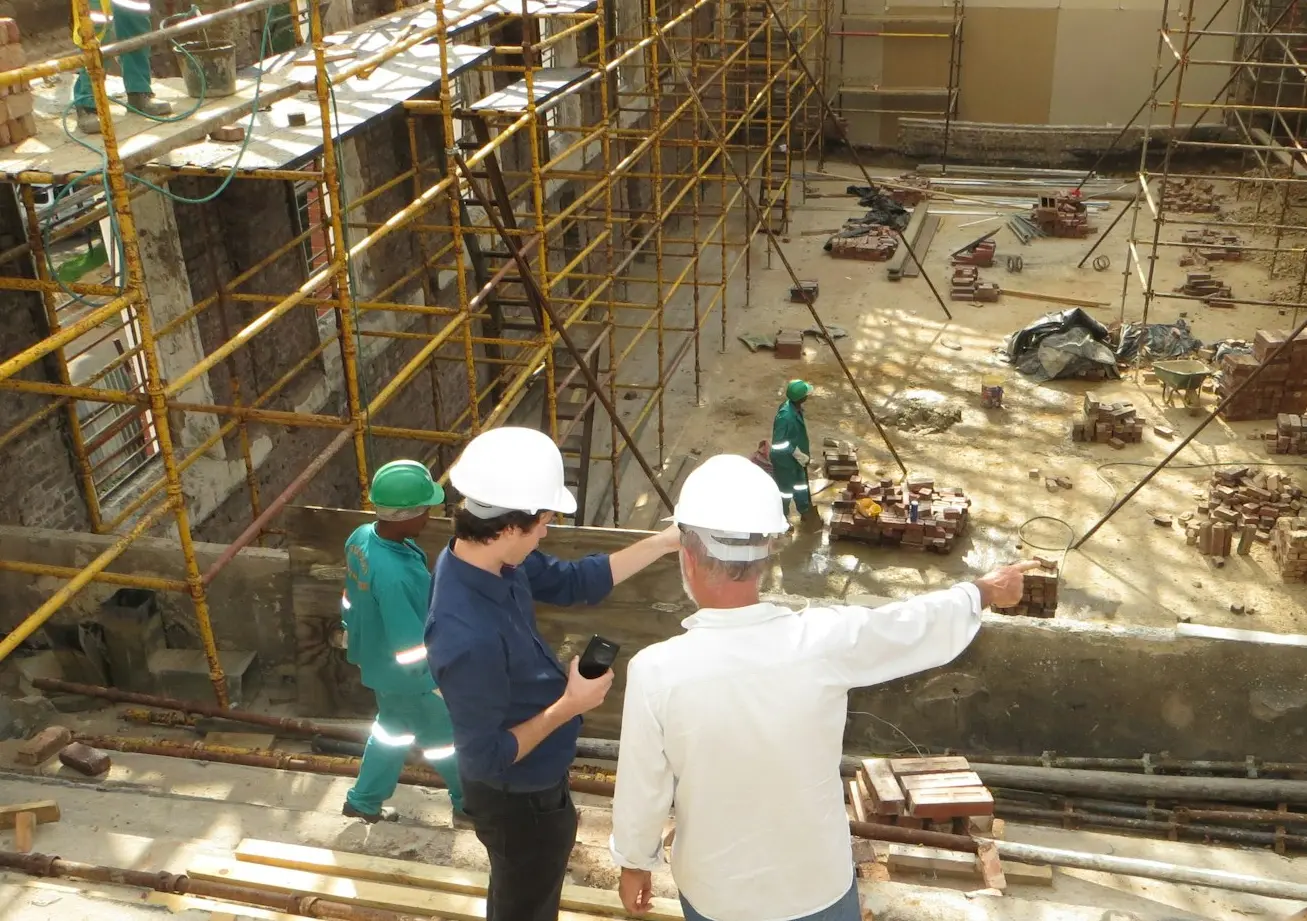man in white long sleeve shirt and blue denim jeans standing on white metal ladder